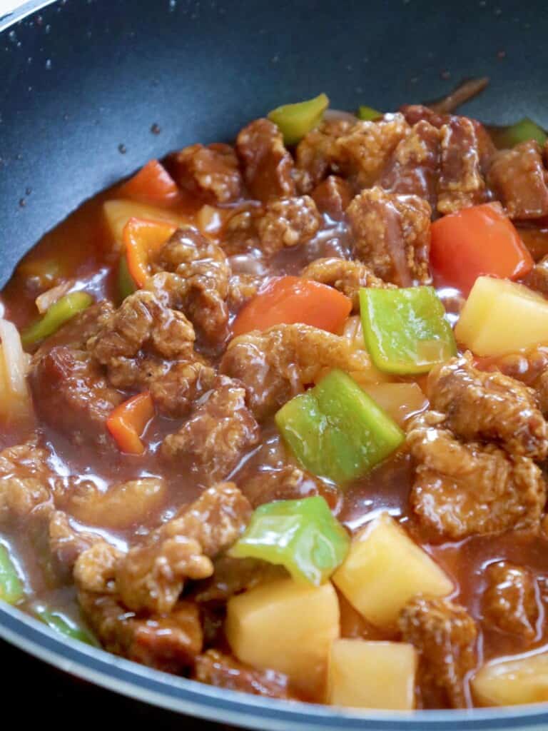 crispy pork cubes in a sweet and sour sauce with bell peppers and pineapple chunks