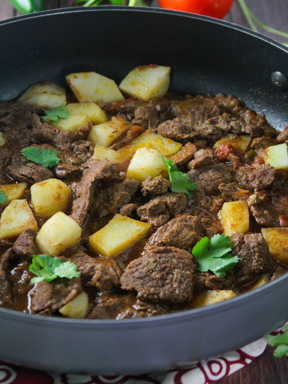 Carne guisada with tender beef, potatoes and spicy tomato sauce in a blue skillet