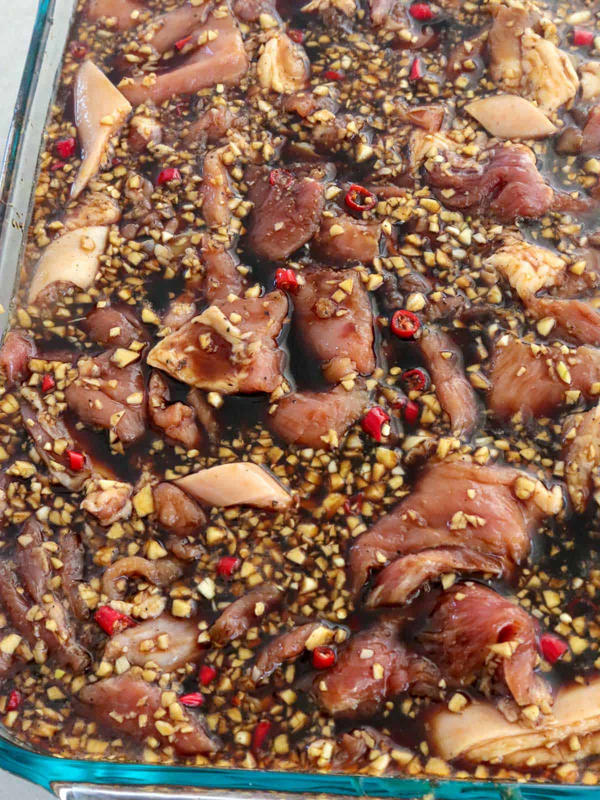 sliced pork marinating in a FIlipino-style barbecue sauce in clear container