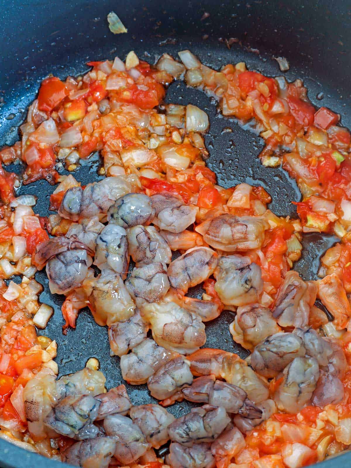 sauteed onions, garlic,, tomatoes, and shrimp in a pot