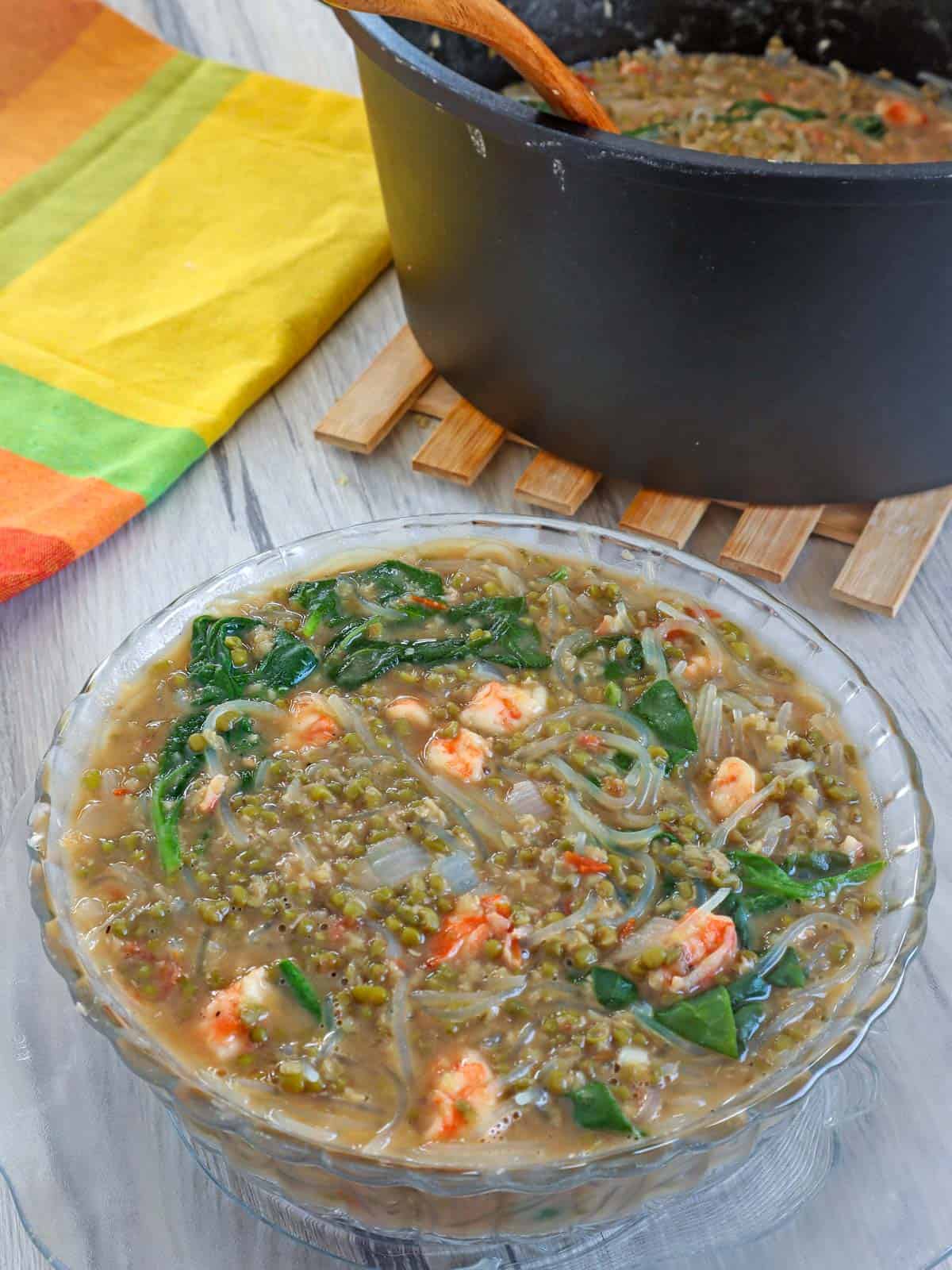 Ginisang Munggo at Sotanghon in a clear glass bowl with a pot of munggo on the side