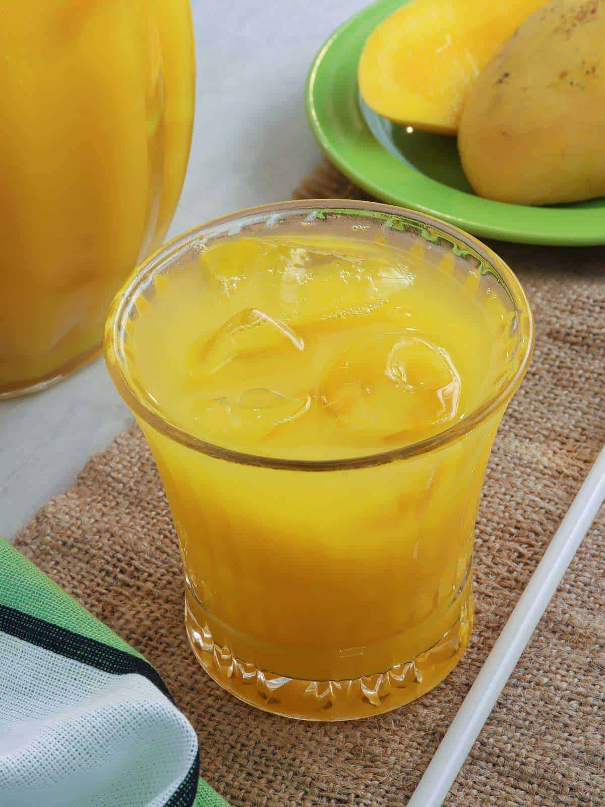 mango juice in a clear glass with pitcher on the side