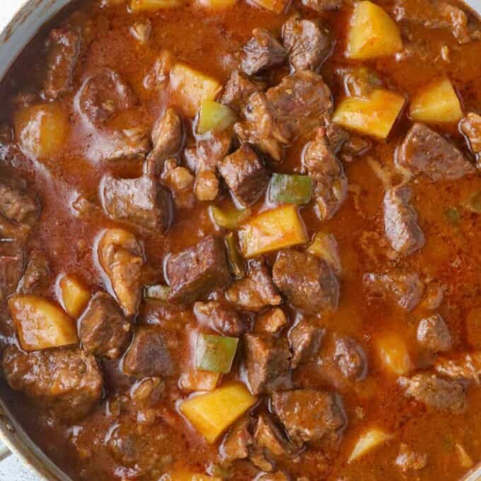 Tex-mex beef stew with potatoes and peppers in pot.