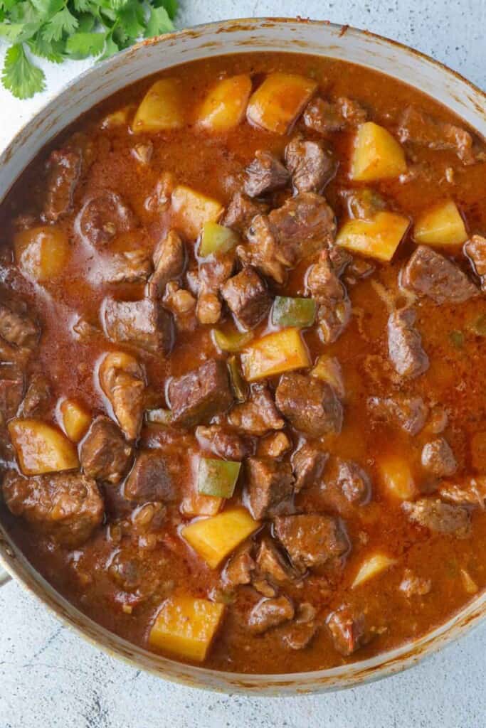 Tex-mex beef stew with potatoes and peppers in pot.