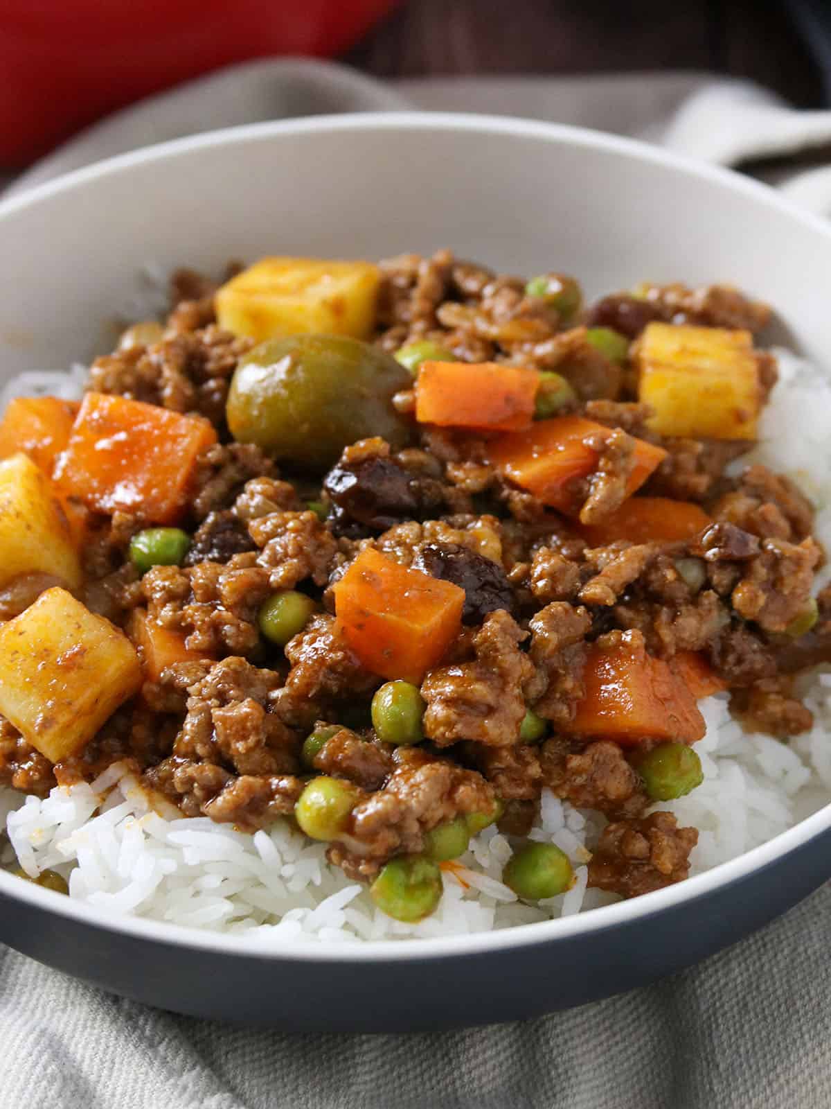 Filipino picadillo served over steamed rice on a plate