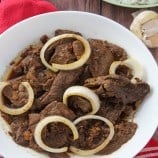 Filipino beefsteak with onions in a white serving bowl