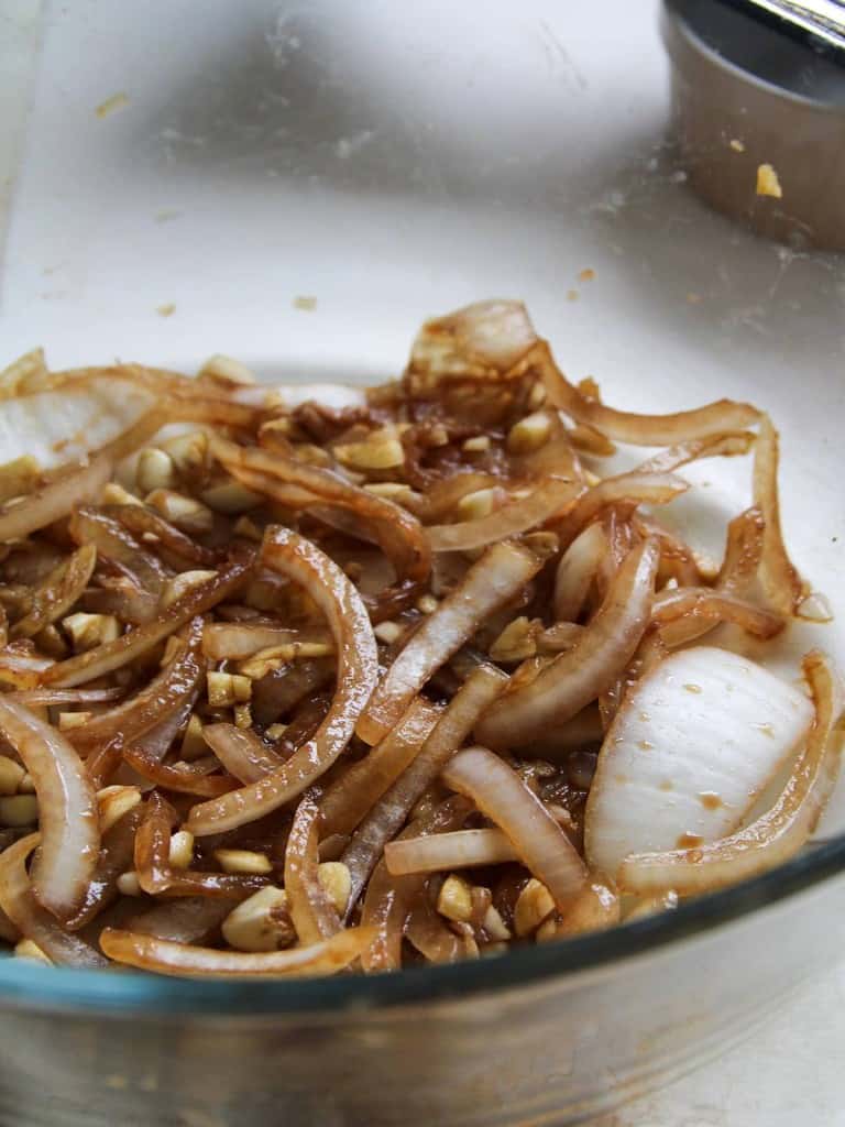 sliced onions, minced garlic, lemon juice, and soy sauce marinade in a clear bowl