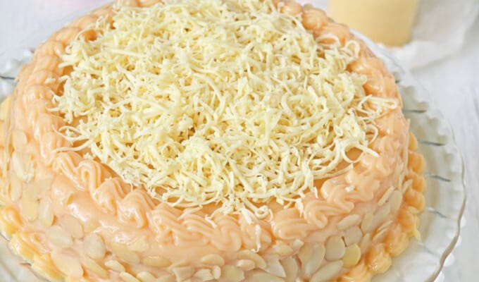 Yema cake made of sponge cake, yema spread, and grated cheese on a serving platter