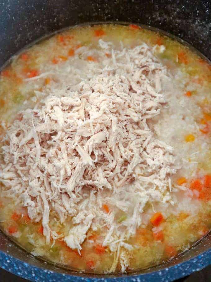 adding shredded chicken to rice porridge in a pot