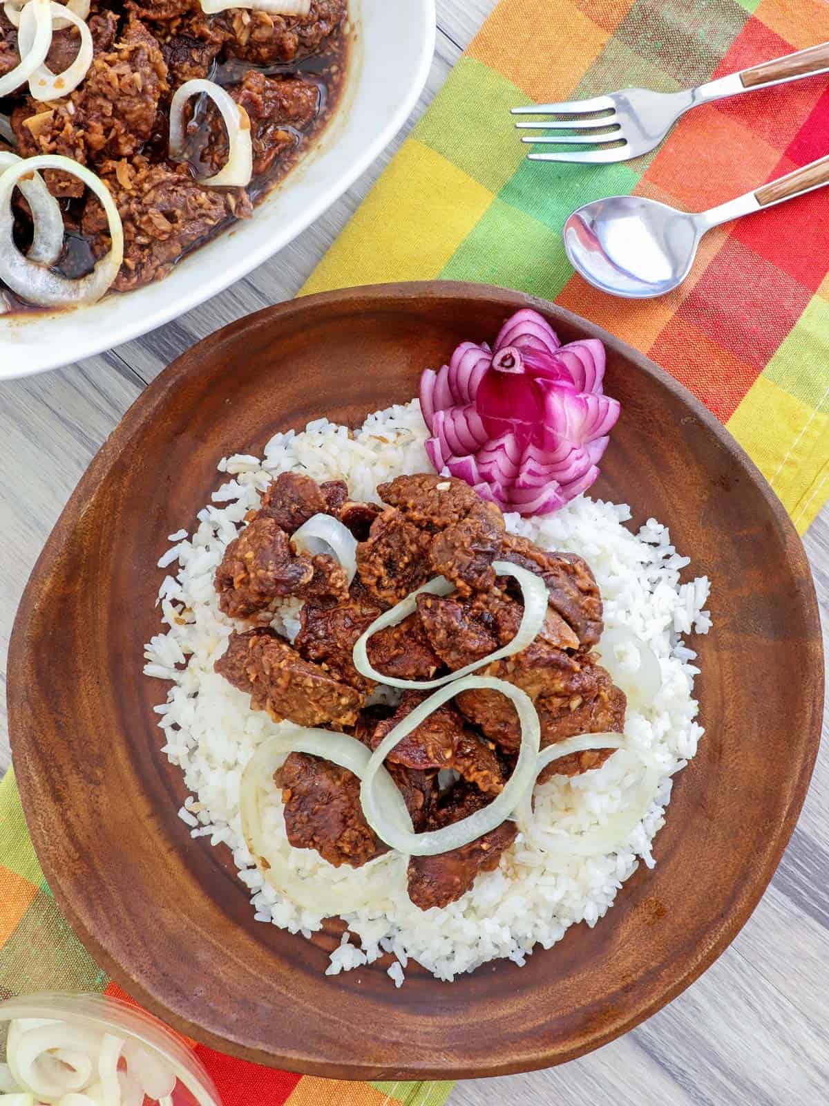cirspy fried chicken livers with onions over rice on a wooden plate
