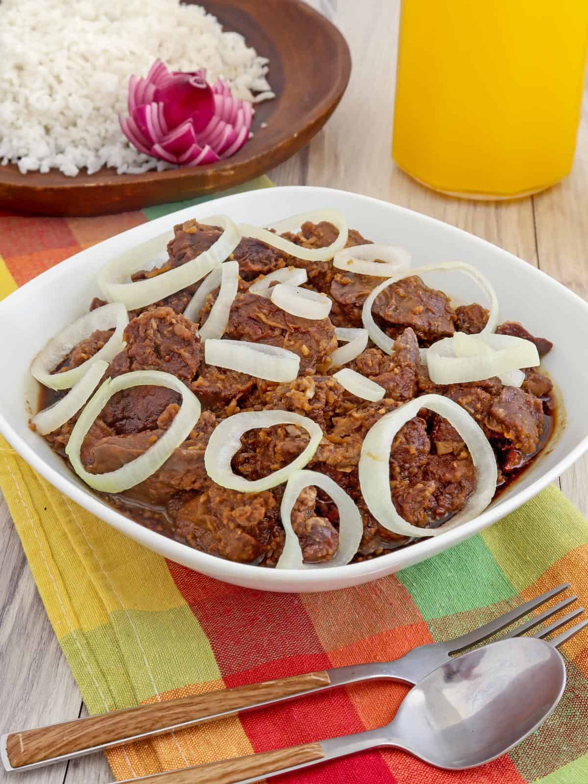 Crispy Chicken Livers a la Bistek topped with onions in a white bowl