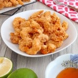 cirspy shrimp in a white serving bowl with a dipping sauce on the side