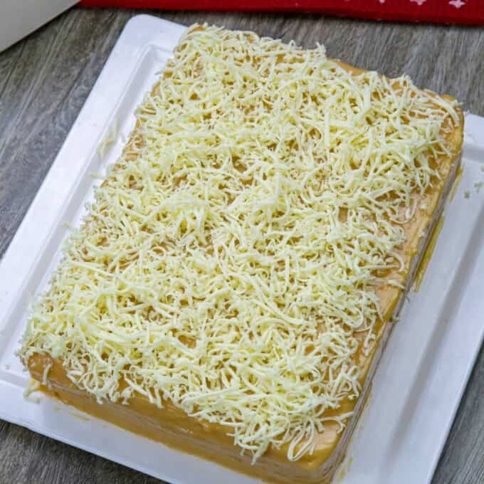 Yema cake made of sponge cake, yema spread, and grated cheese on a serving platter.
