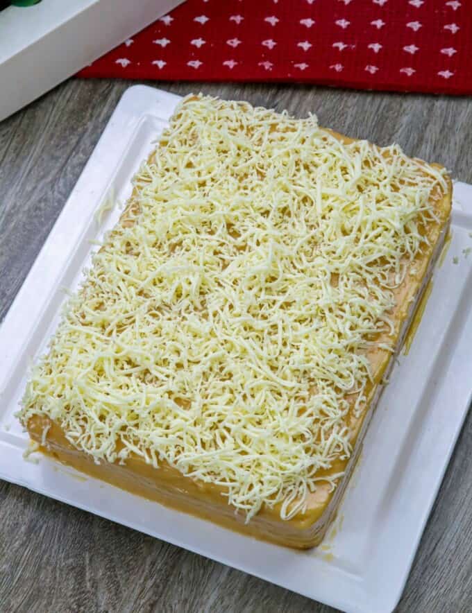 Yema cake made of sponge cake, yema spread, and grated cheese on a serving platter.