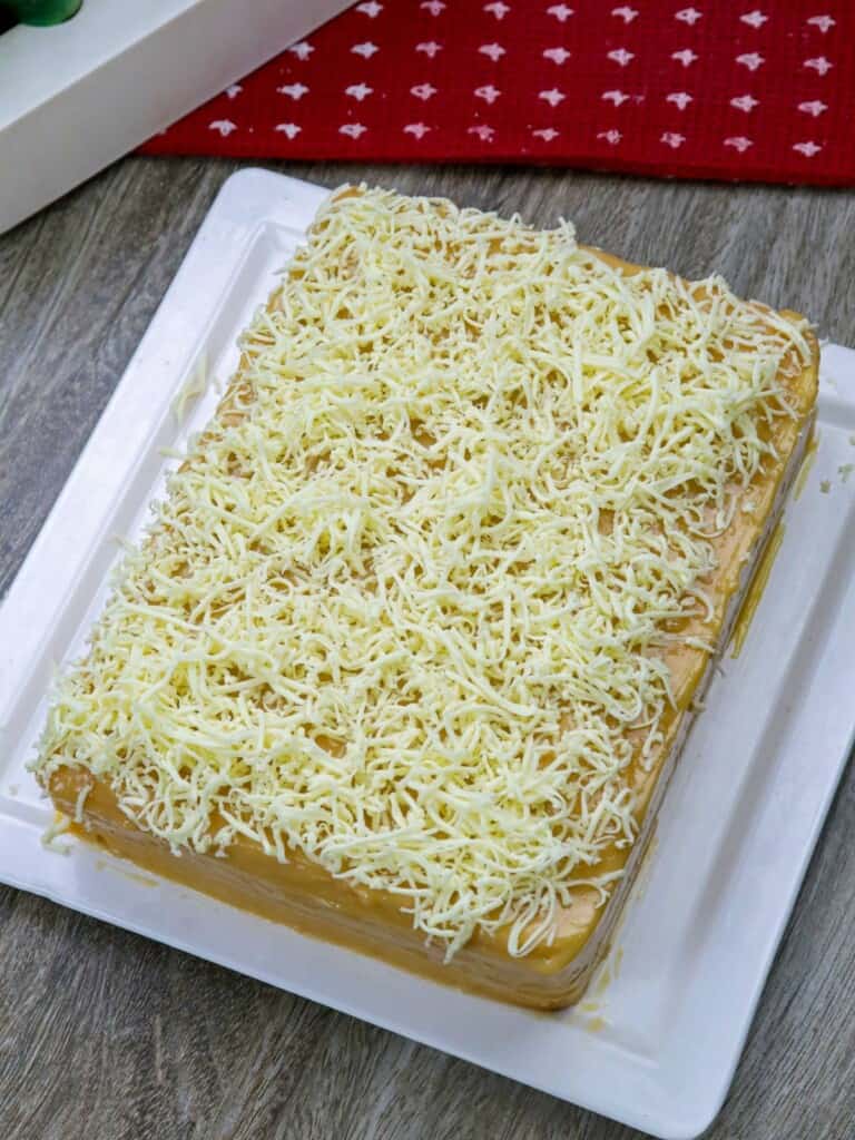 Yema cake made of sponge cake, yema spread, and grated cheese on a serving platter.