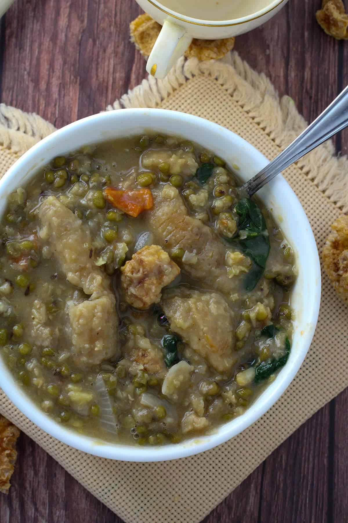 munggo soup with chicharon in a white serving bowl