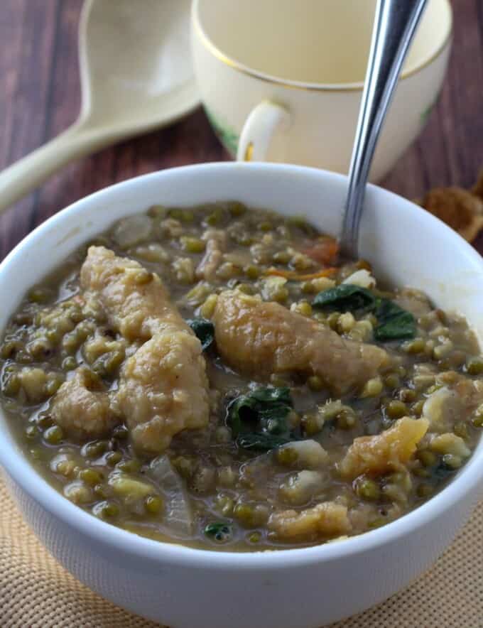 serving mung bean stew with crispy pork cracklings from a white serving bowl