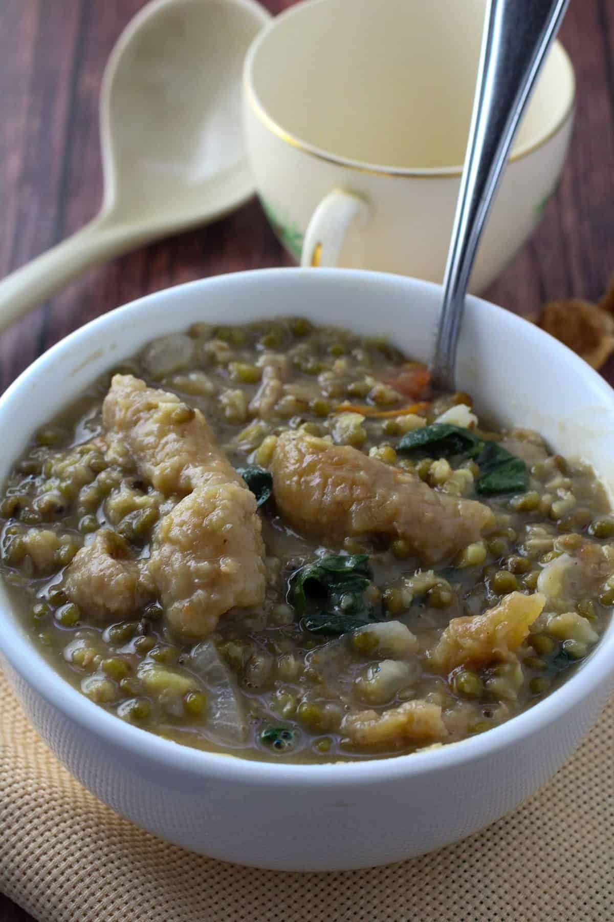 serving mung bean stew with crispy pork cracklings from a white serving bowl