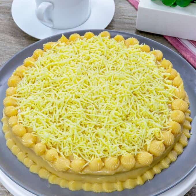 Yema cake made of sponge cake, yema spread, and grated cheese on a serving platter.