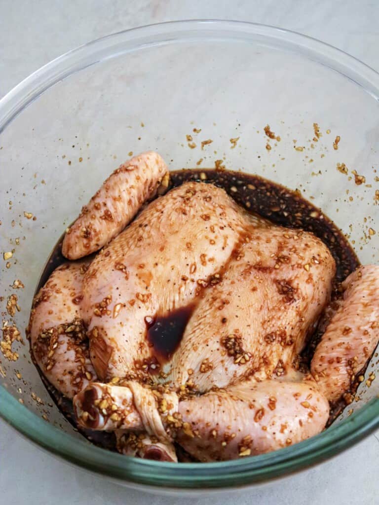 butterflied chicken marinating in BBQ marinade in a bowl