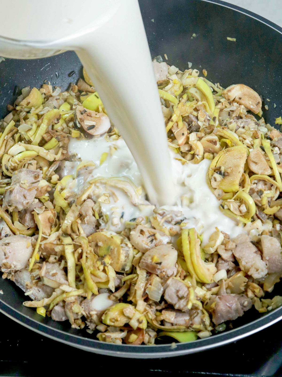 adding coconut milk to sauteed banana blossom in a pan