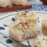 eating steamed cassava cakes topped with grated coconut on a plate