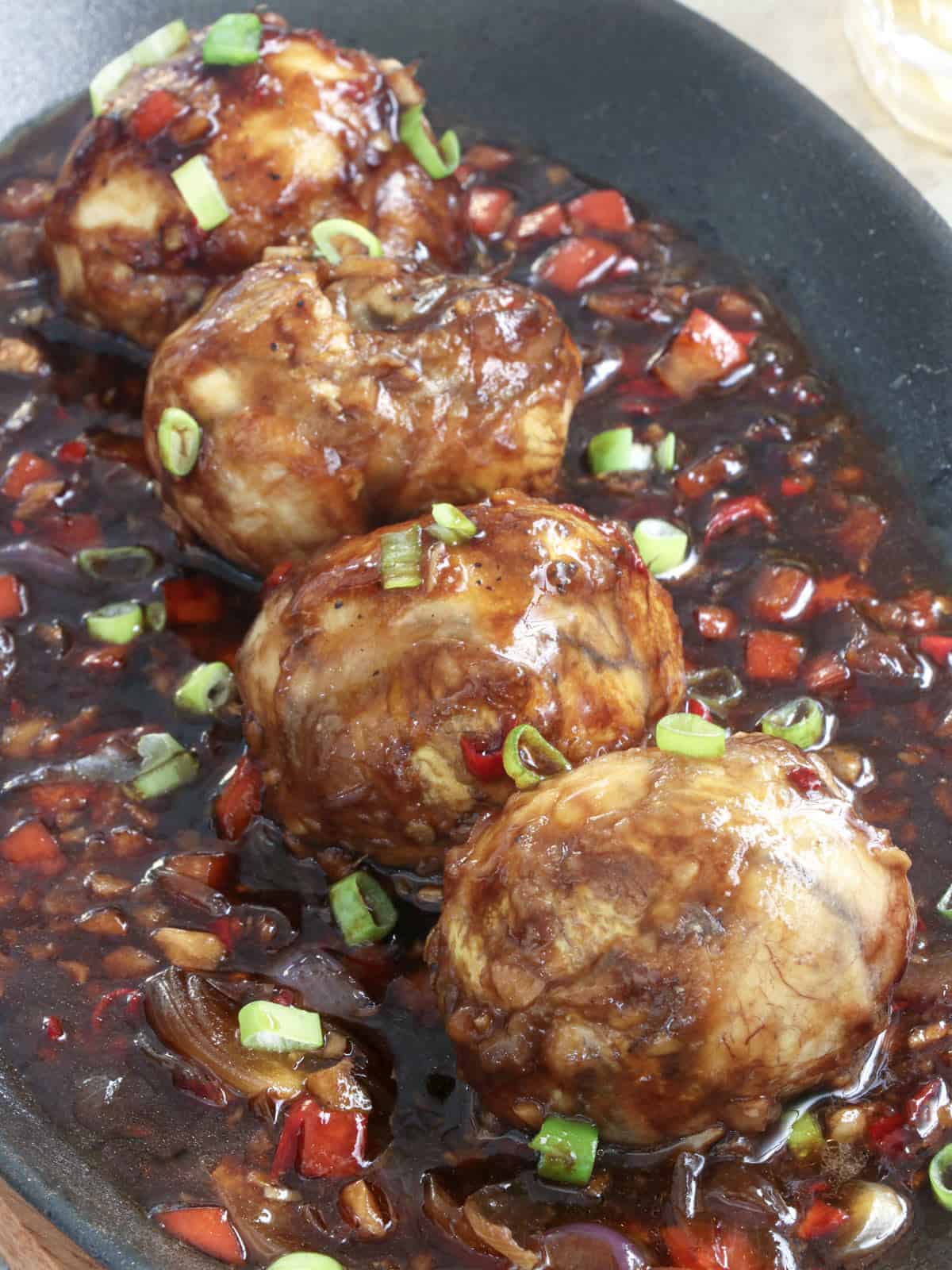 balut with a spicy sauce in a cast iron skillet