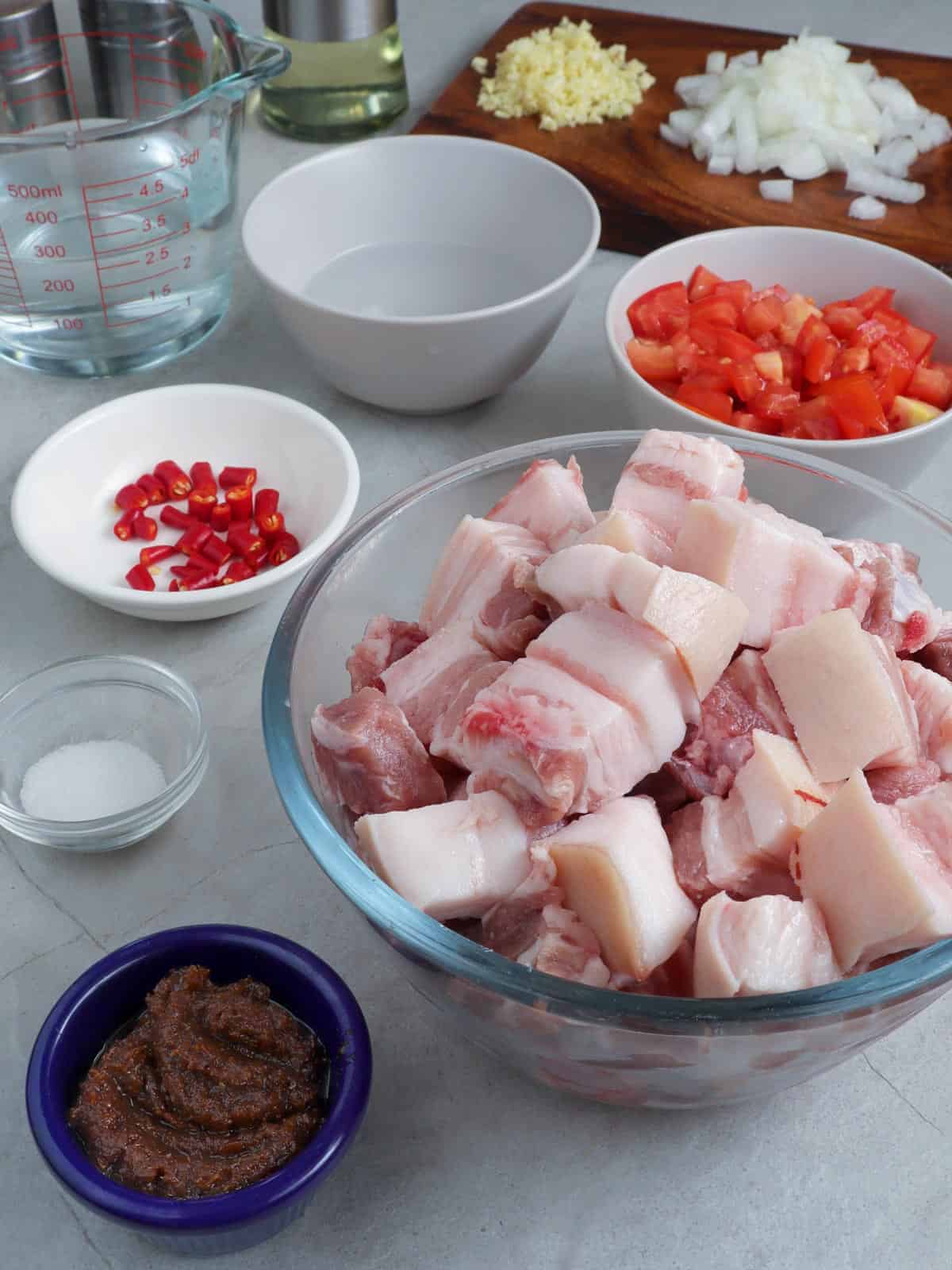 diced pork belly, chopped tomatoes, shrimp paste, minced chili peppers, water, vinegar, salt in individual bowls