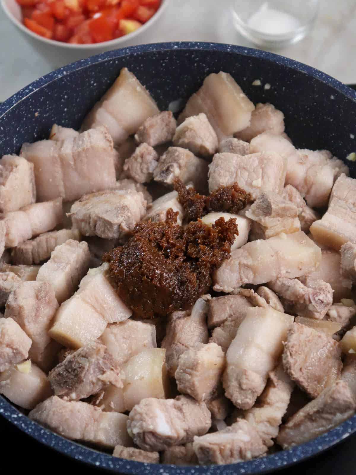 sauteing pork belly with shrimp paste in a pan