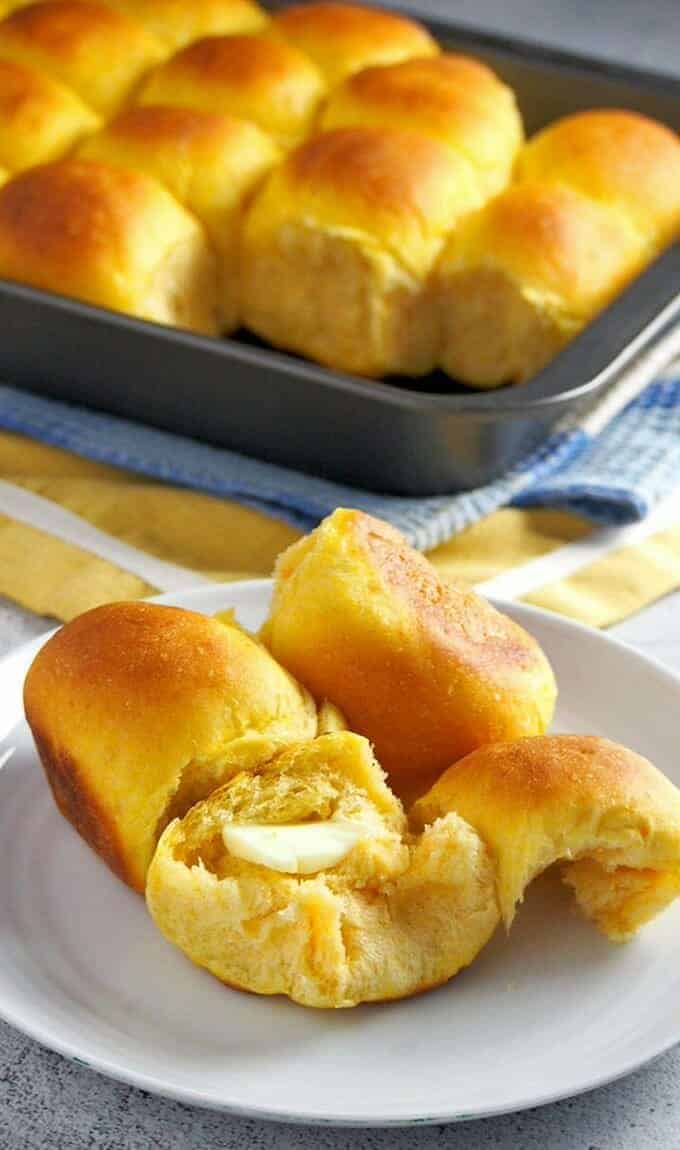 homemade sweet potato rolls with butter on a white plate