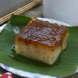 slice of bibingkang malagkit on a banana-lined white serving plate with cup of coffee in the bakcground.