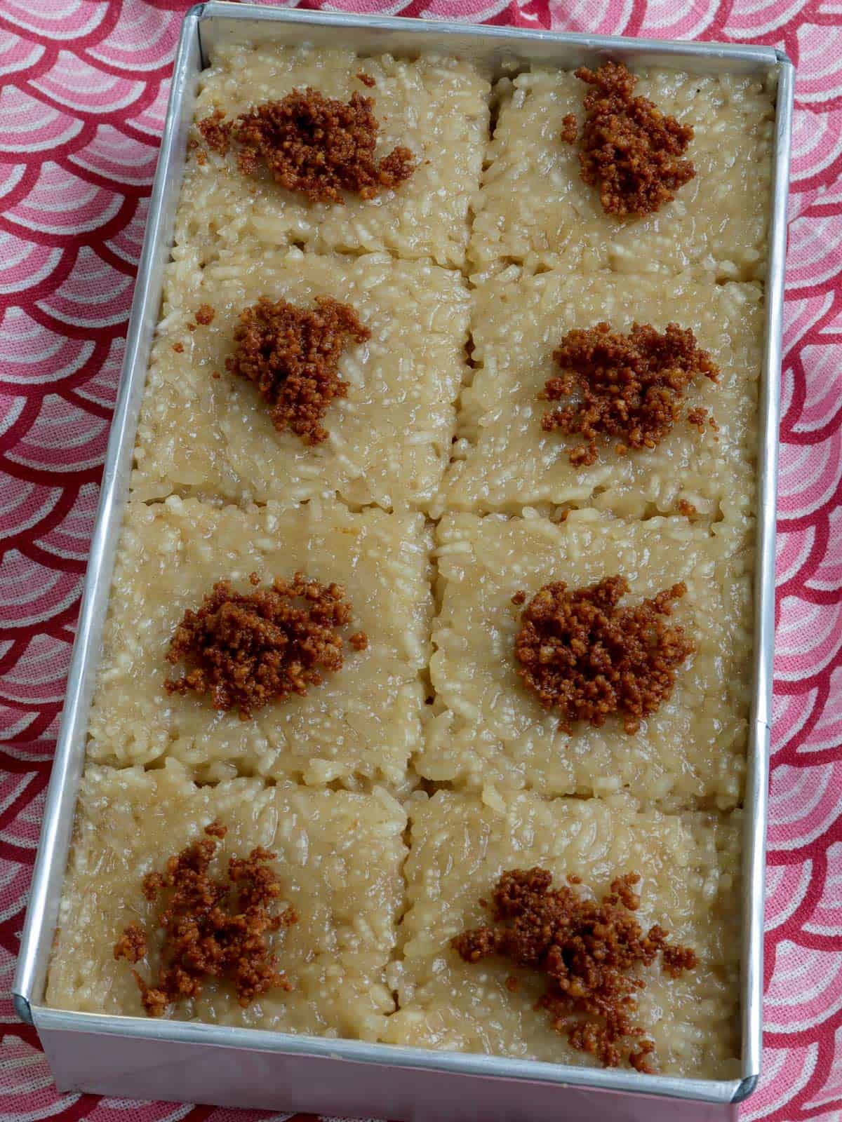 sliced biko in a rectangular pan with latik topping