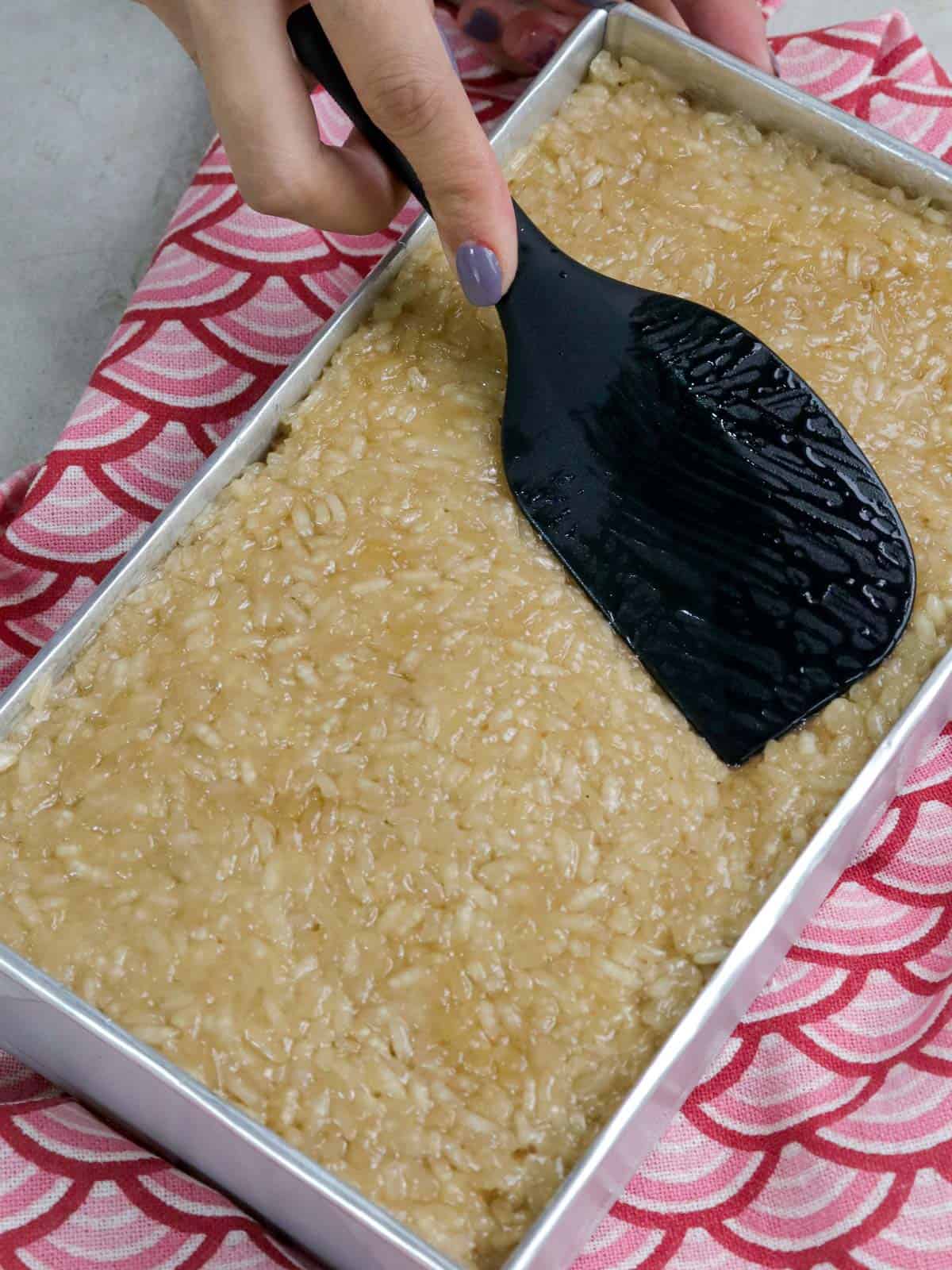 placing cooked biko in a rectangular pan