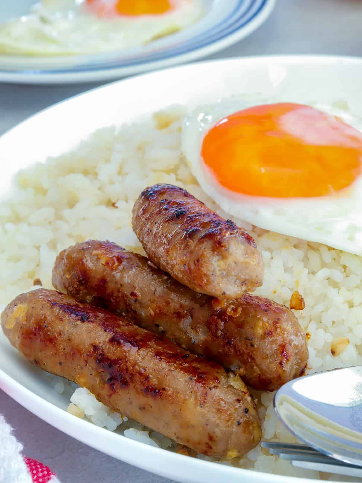 Skinless Longganisa on a serving plate with fried eggs and garlic fried rice