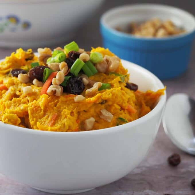 Kabocha Salad in a white bowl with bowls of shredded carrots and peanuts on the side