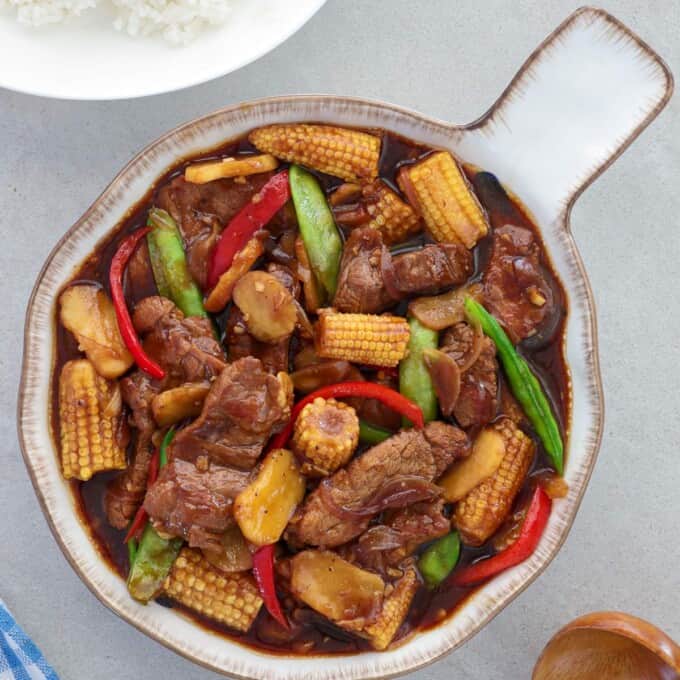 beef and baby corn stir fry in a serving bowl.