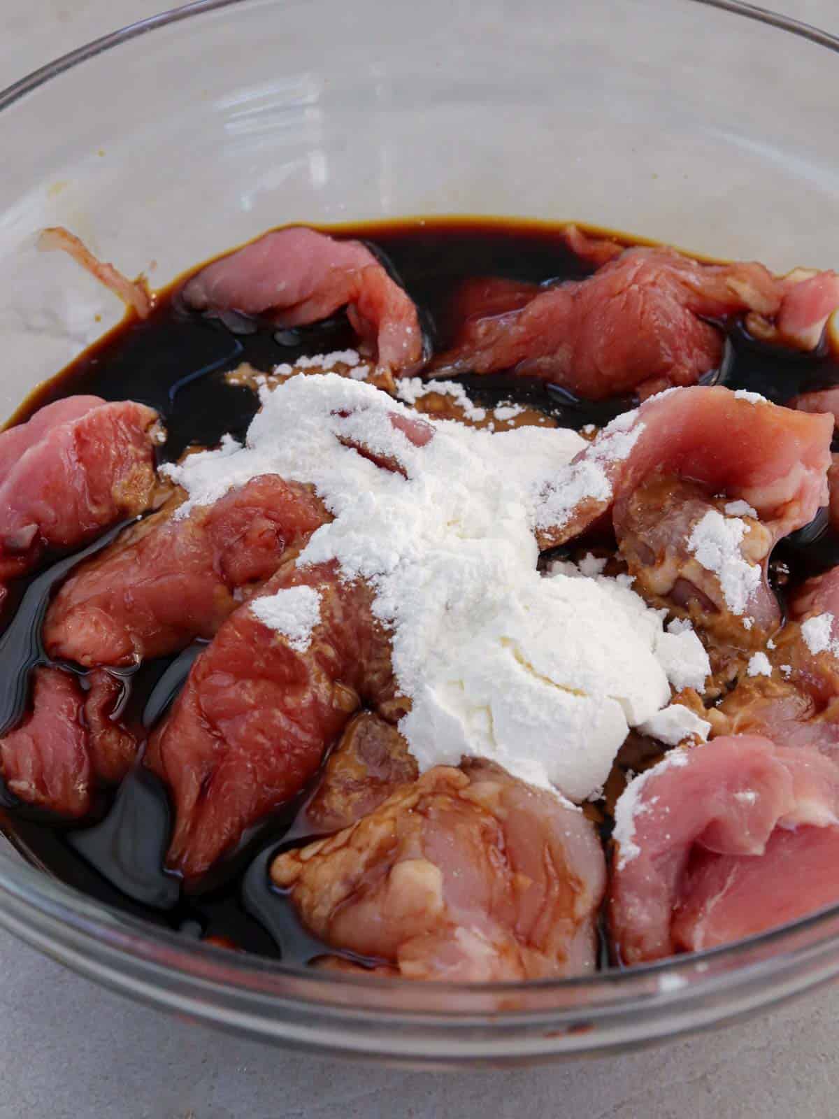 velveting beef slices in a glass bowl.