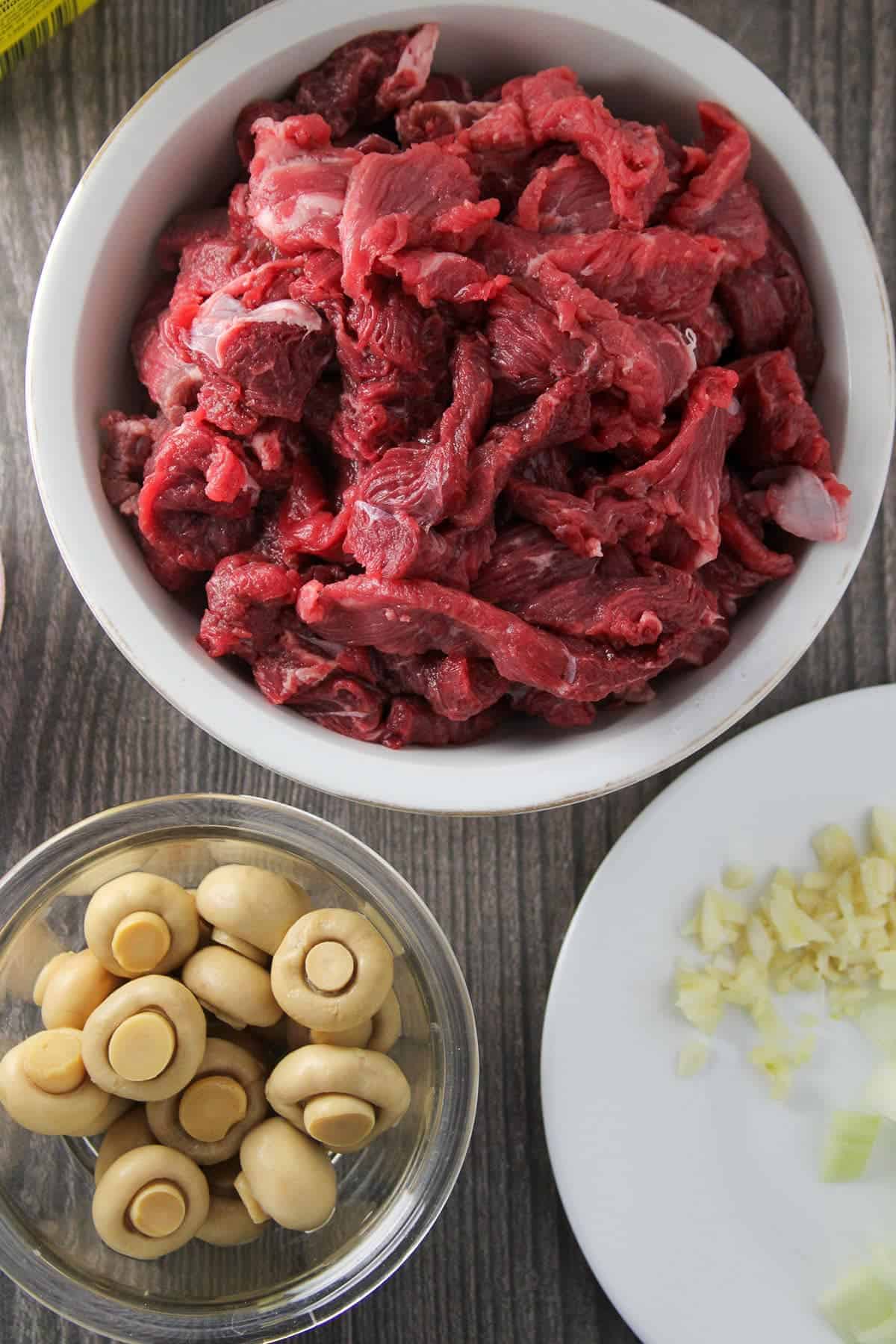 sliced beef, button mushrooms, and minced garlic in bowls