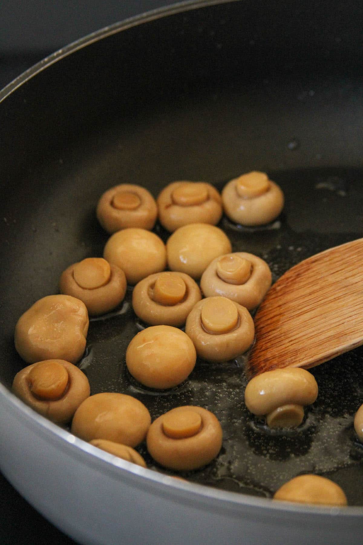 sauteing button mushrooms in a pan