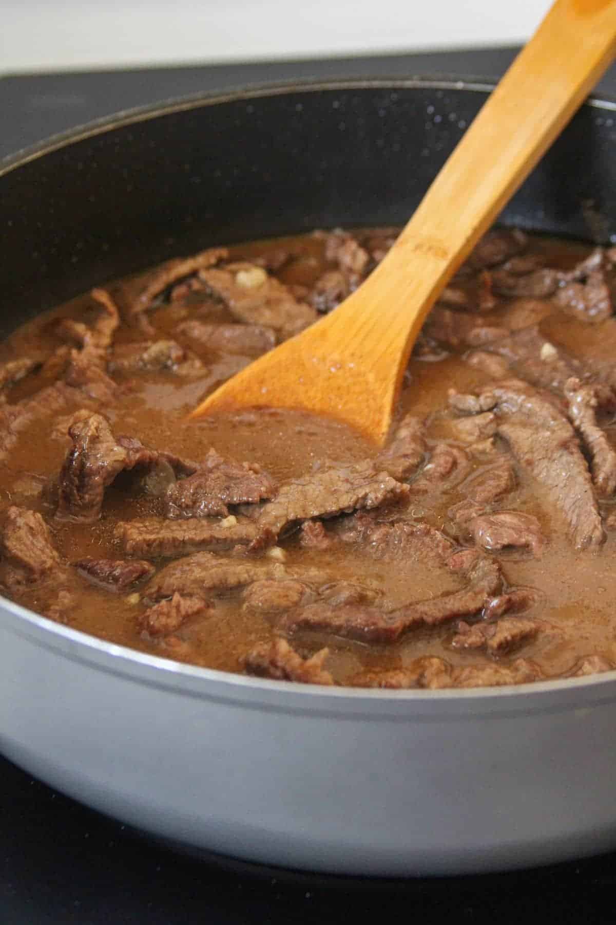 cooking beef in pan with mushroom sauce