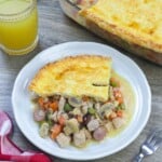 slice of Filipino-style chicken pot pie on a white plate with the whole pie in the background.