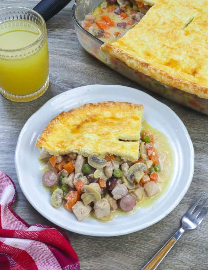slice of Filipino-style chicken pot pie on a white plate with the whole pie in the background.