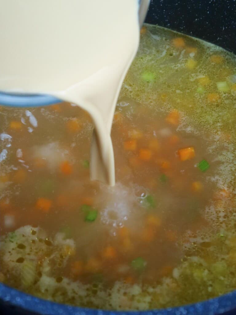 pouring evaporated milk to sopas in a pot