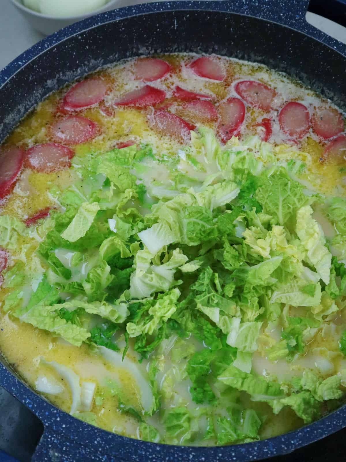 making chicken sopas in a pot with napa cabbage