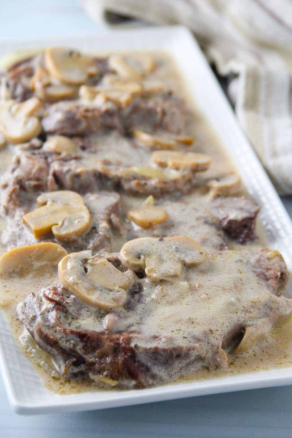 Lengua in Mushroom Sauce on a white serving platter