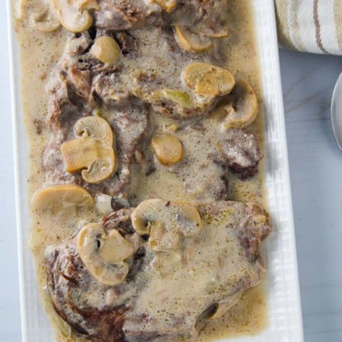 creamy lengua in mushroom gravy on a white serving platter