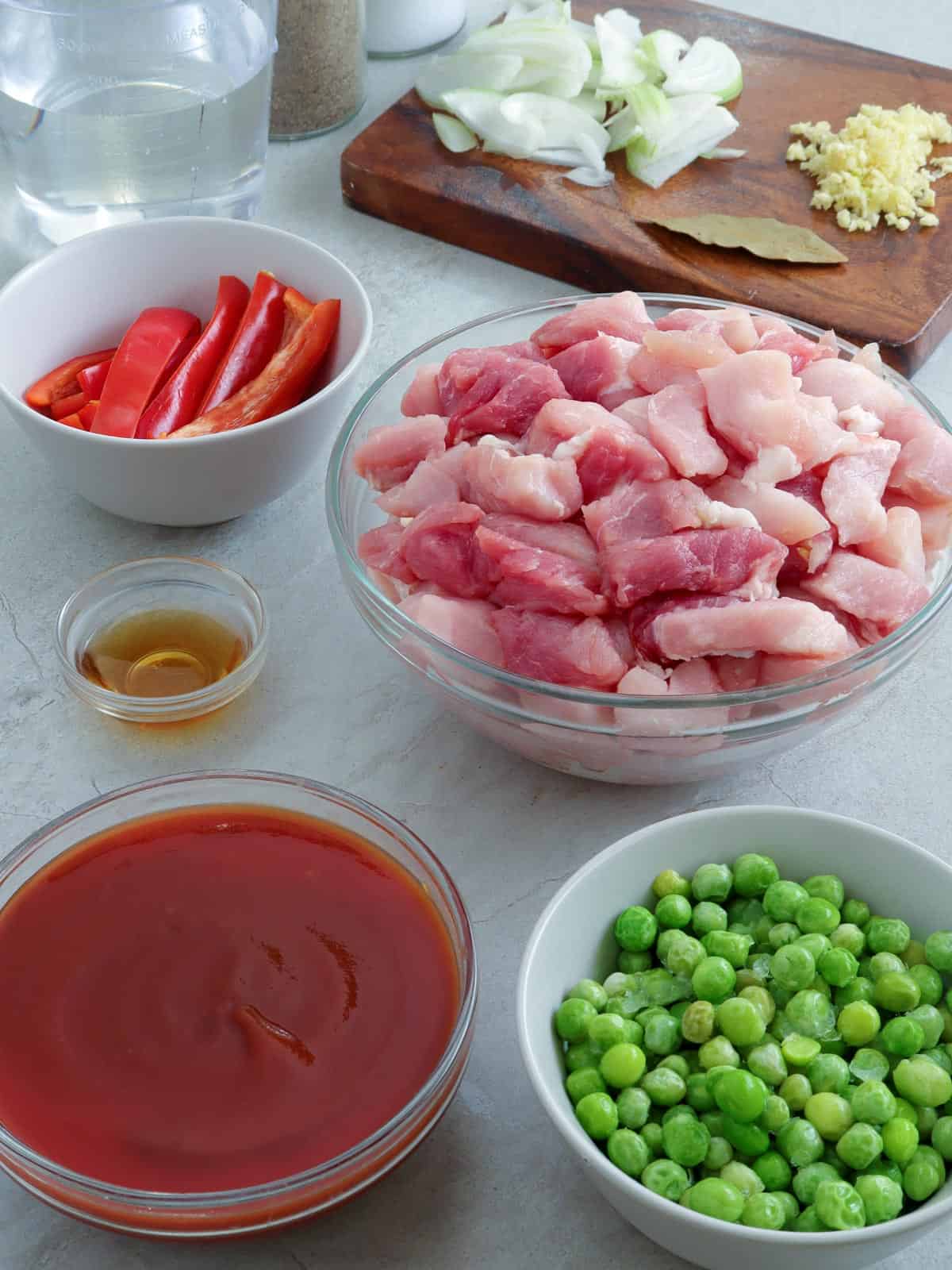pork strips, green peas, bell pepper strips, tomato sauce, fish sauce, chopped onions, minced garlic, bay leaves