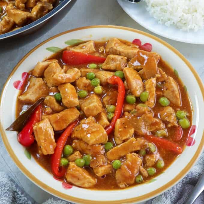 Pork Guisantes in a serving bowl with plate of steamed rice on the side