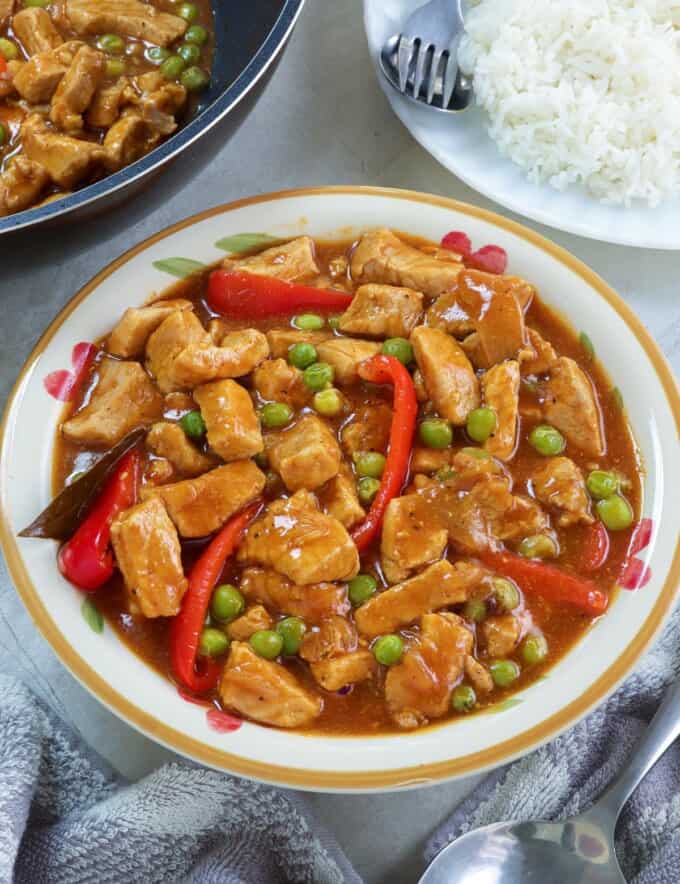 Pork Guisantes in a serving bowl with plate of steamed rice on the side