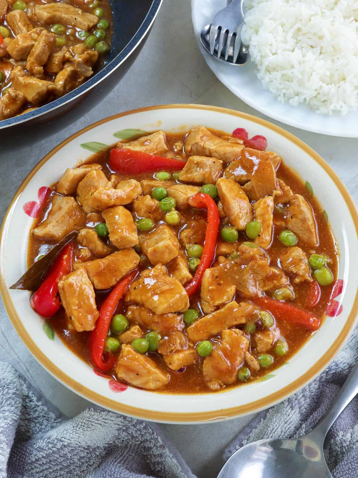 Pork Guisantes in a serving bowl with plate of steamed rice on the side